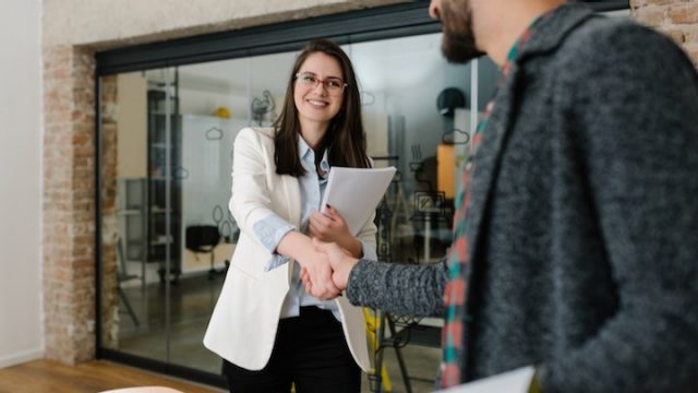 Smiling woman shakes man's hand
